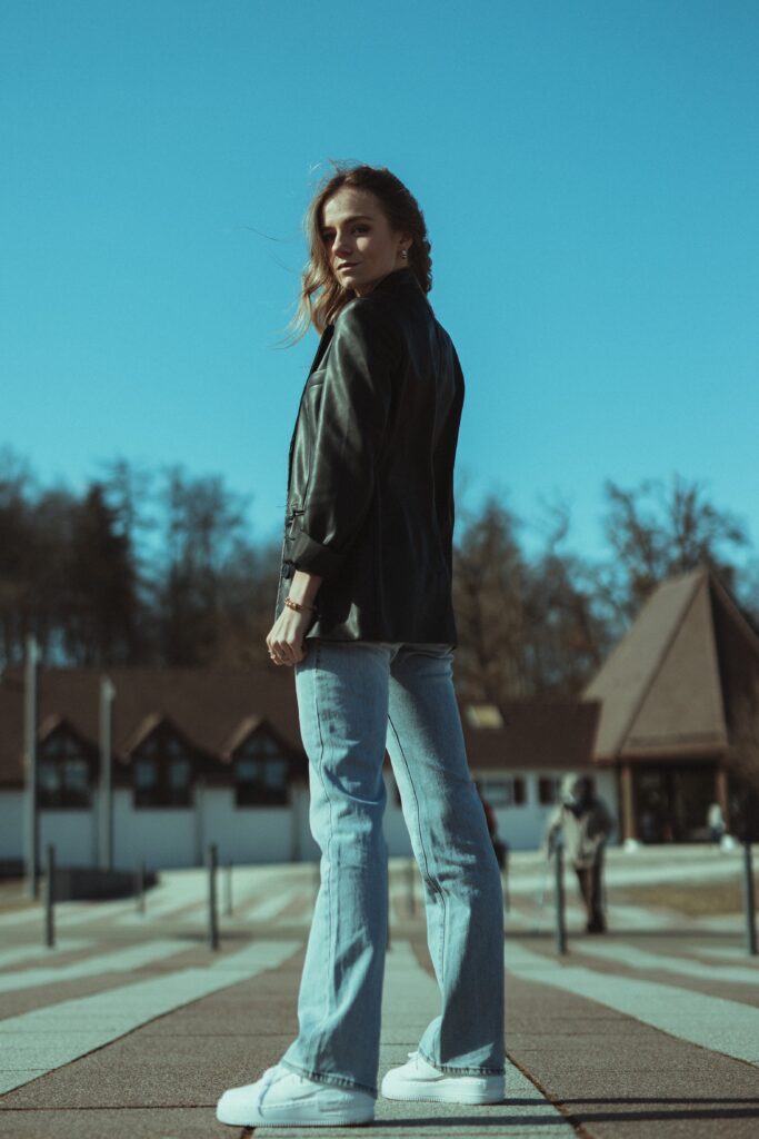Woman standing in black leather jacket and jeans looking strong.